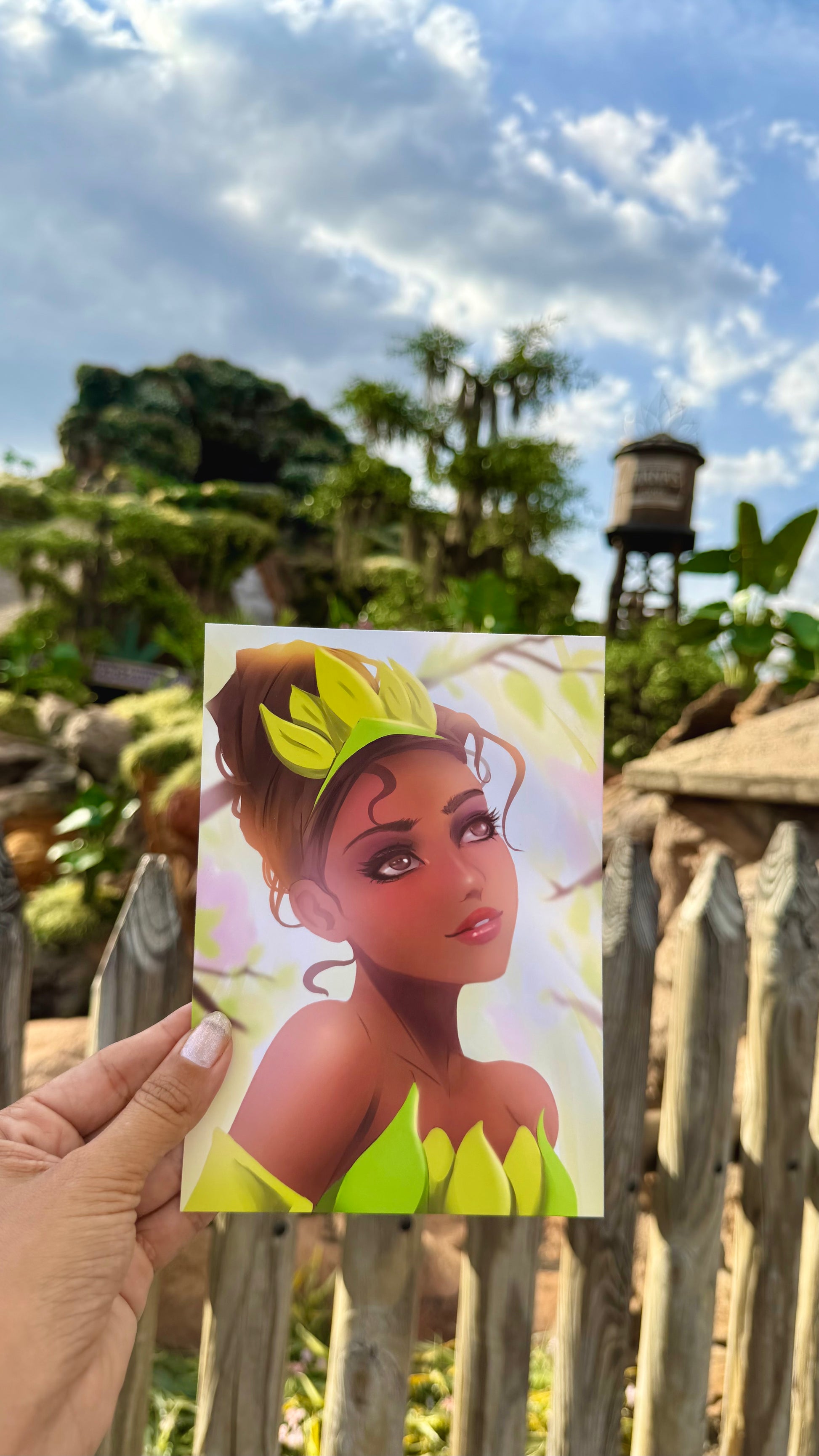 Person holding a picture of Tiana in front of a themed background